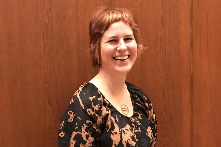 Jessica Grzegorski in 2024: smiling and standing against a wood panelled wall