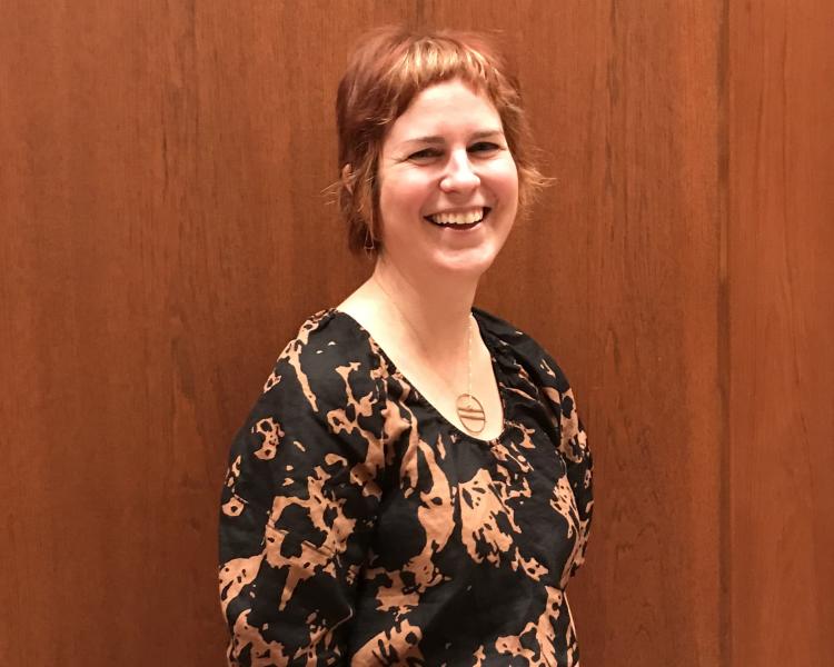 Jessica Grzegorski in 2024: smiling and standing against a wood panelled wall